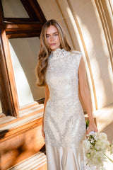 Brunette model wearing the Nicoletta High Neck Gown in Gold content shot